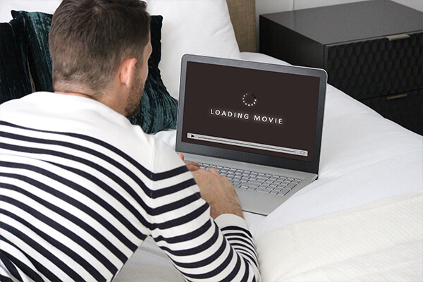 Mann liegt am Bett und sieht Netflix