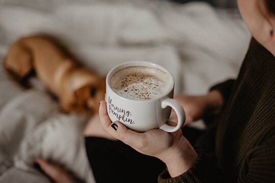 Frau trinkt gemütlich Kaffee im Bett