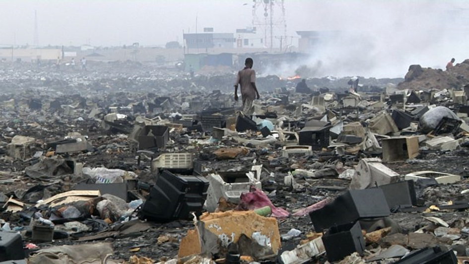 Persoon die over een e-waste stortplaats loopt. Foto gelicentieerd onder CC BY-SA.