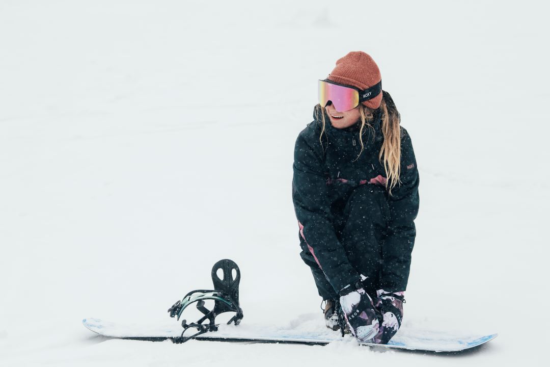 Frau zieht sich Snowboard an