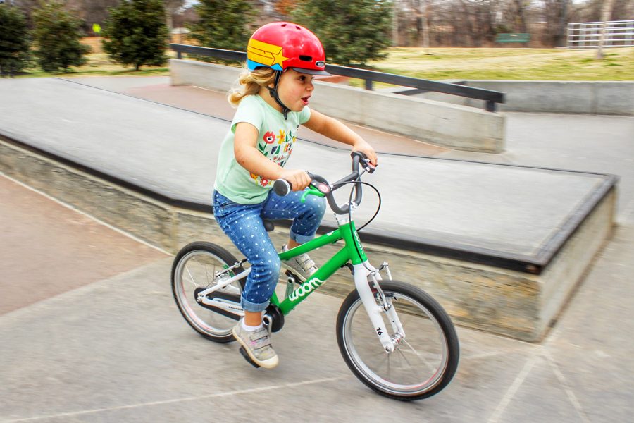 Mädchen fährt mit einem grünen Woom-Fahrrad im Skatepark – perfektes Kinderfahrrad für Abenteuer.
