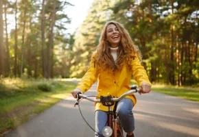Kvinde cykler langs en sti med træer
