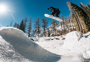 Snowboarder hopper over en snedækket bjergryg
